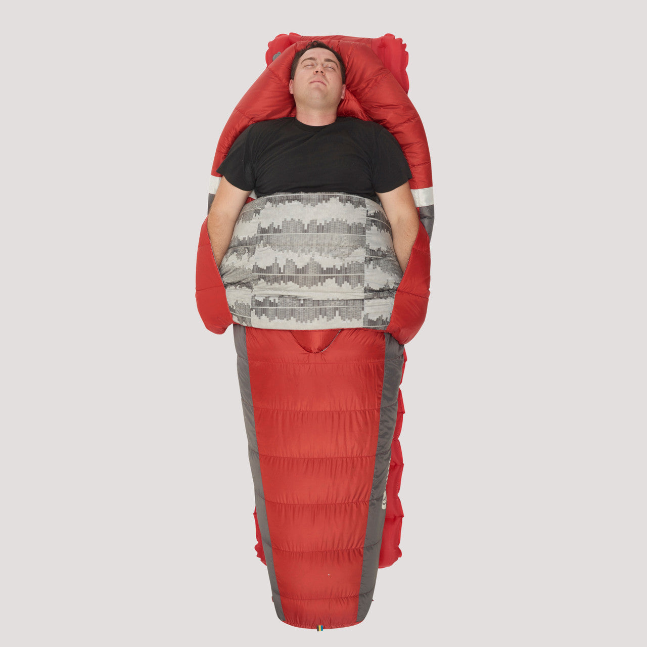 Man sleeping on his back in Sierra Designs Backcountry Bed 650 / 20 Degree sleeping bag, with bag opened