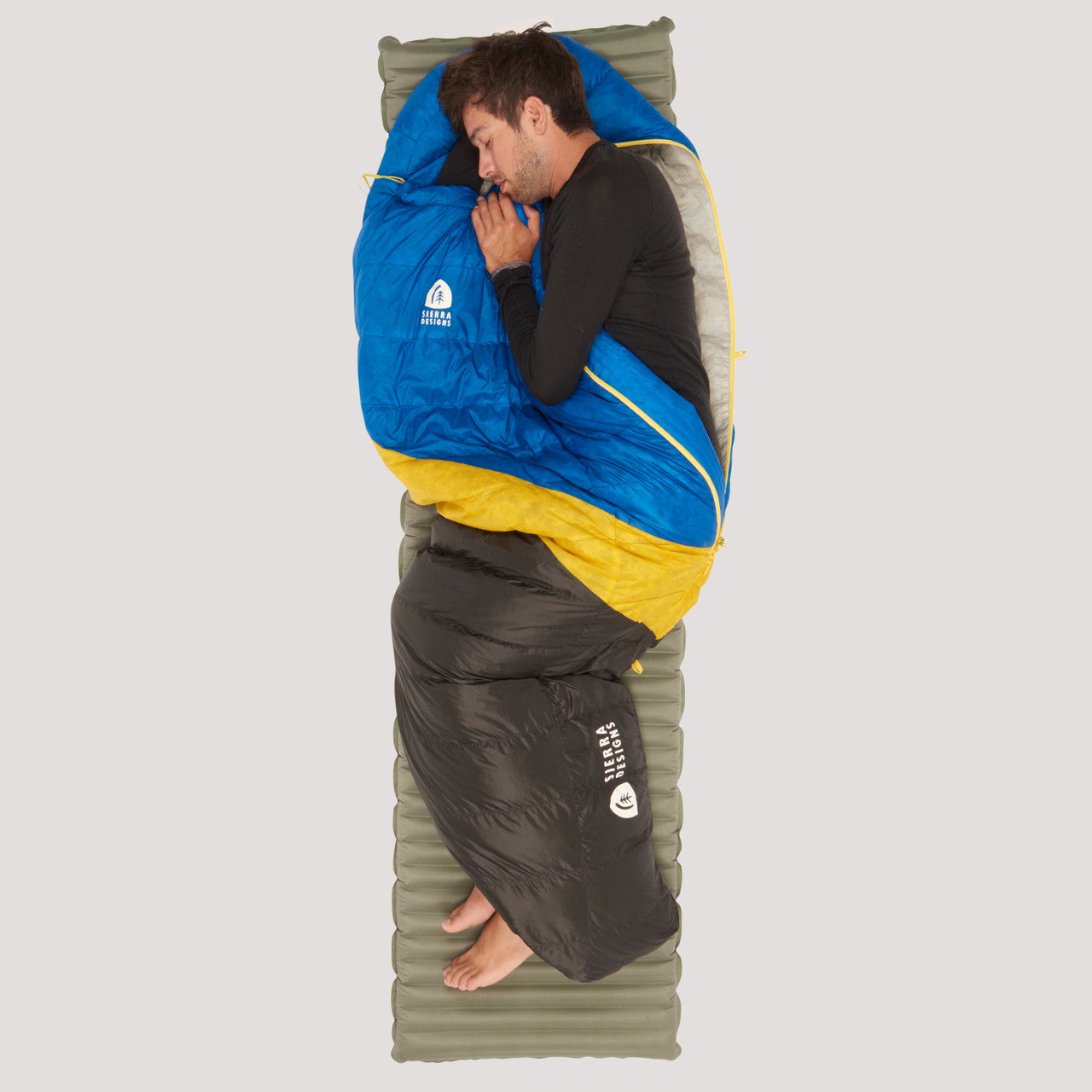 Sierra Designs Nitro 35 sleeping bag, blue/black with yellow stripe, front view, partially opened, with man sleeping on side